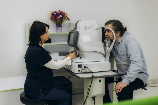 Patient receiving eye examination with autorefractor by optician