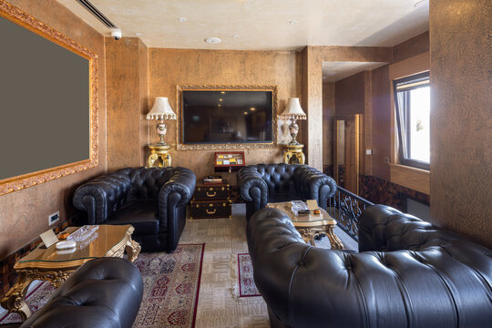 Luxury lounge interior with black leather chesterfield armchairs and golden walls