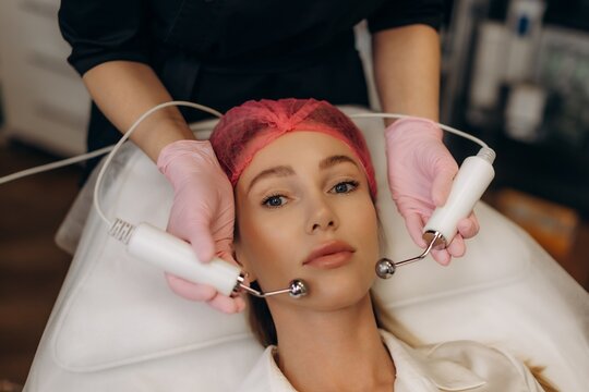 Young woman receiving microcurrent facial therapy in spa