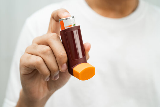 Asthma and chronic obstructive pulmonary disease COPD, Asian young man using metered dose inhaler MDI.