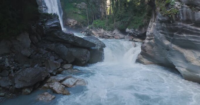 Annapurna Circuit Nepal, aerial gliding shot of white water rapids in the Marsyangdi River gorge with Danaque waterfall dropping from rocky cliffs into the stream channel near Manang.