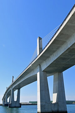 Dynamic low angle vertical view of a large concrete cable stayed bridge looking up at pylons under a clear blue sky, Fukushima Japan.