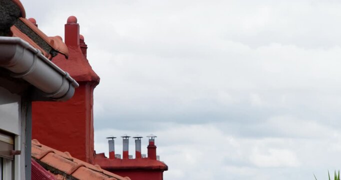 Red Chimneys Against a Cloudy Sky: A close-up view of a vibrant red chimney structure with multiple flues, set against a backdrop of a dramatic, cloud-filled sky.