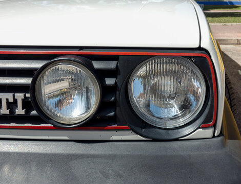 TAVERNES BLANQUES, SPAIN - JUNE 14, 2026.Close view of round headlights and red trimmed front grille on classic white Volkswagen Golf GTI parked under clear sky