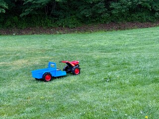Obraz premium Blue and red trailer toy on a green grass. 