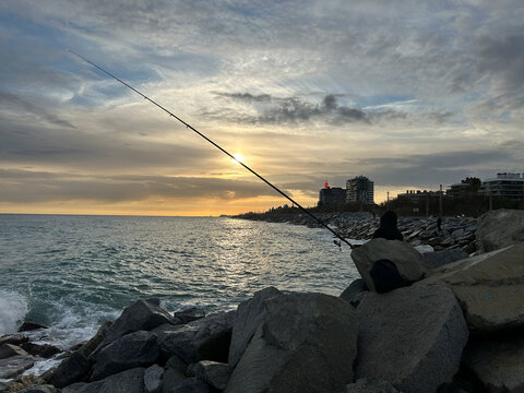 Pescador lanzando su sedal al mar al atardecer