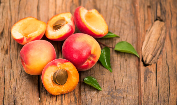 Apricots. Close-up of fresh organic apricot fruits on a rustic wooden table. Fresh bio apricot with leaves closeup, top view 