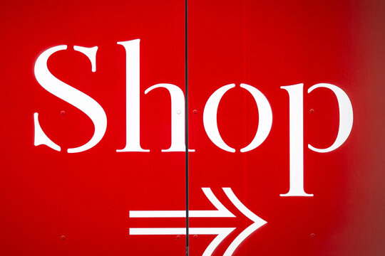 Red signpost pointing to a shop