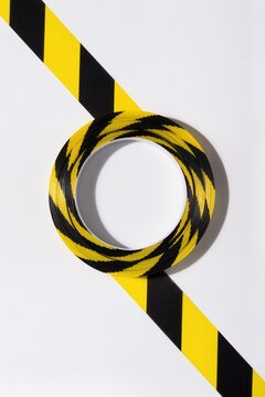 Roll of yellow and black warning tape over diagonal caution stripe