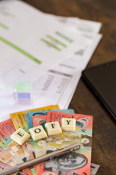 EOFY tax time concept with banknotes and pen on desk by phone