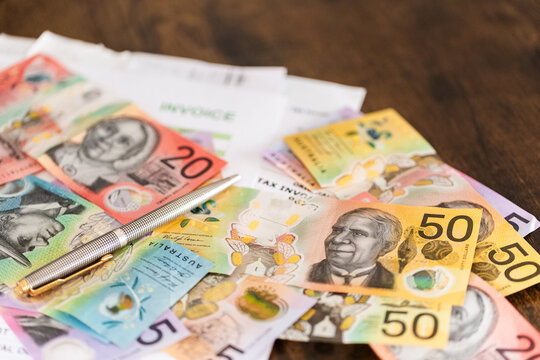 pen and colourful Australian banknotes scattered on tax invoices EOFY concept