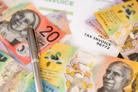 pen and colourful Australian banknotes scattered on tax invoices EOFY concept