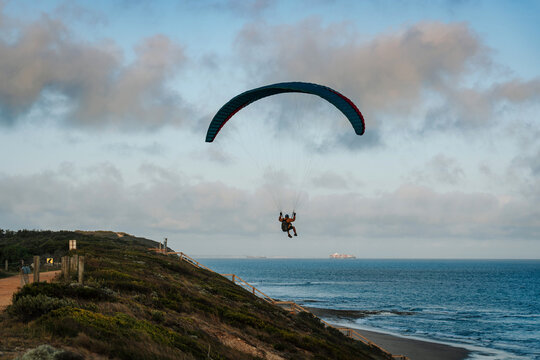 Paraglider soaring gracefully above the ocean at twilight
