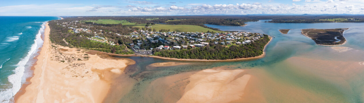 Aerial panorama view of a small seaside town between an inland river system and a sandy coastline