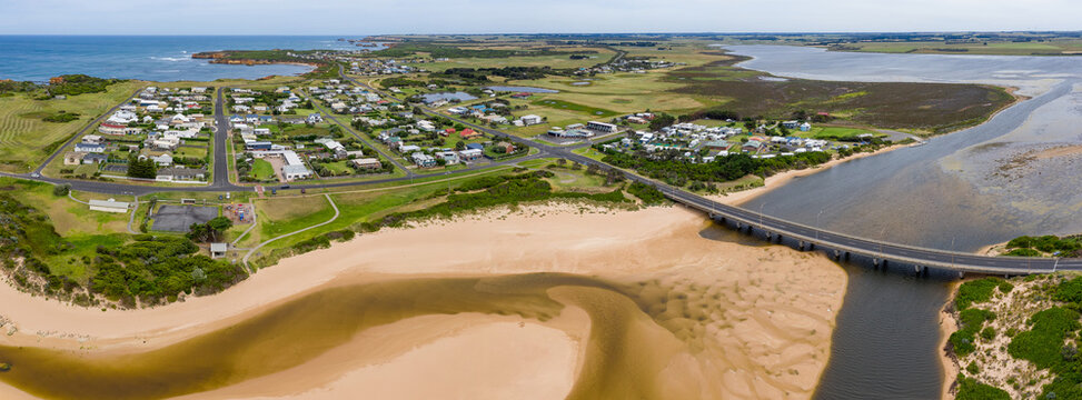 Aerial panorama view of a bridge over a coastal river flowing alongside a small town