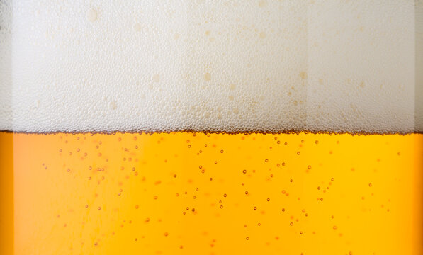Beer with bubbles in glass close up macro background 