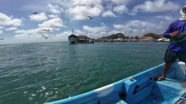 Skilled local fisherman casts a traditional net from a small blue boat, capturing the authentic daily routine of sustainable artisanal fishing at sea.