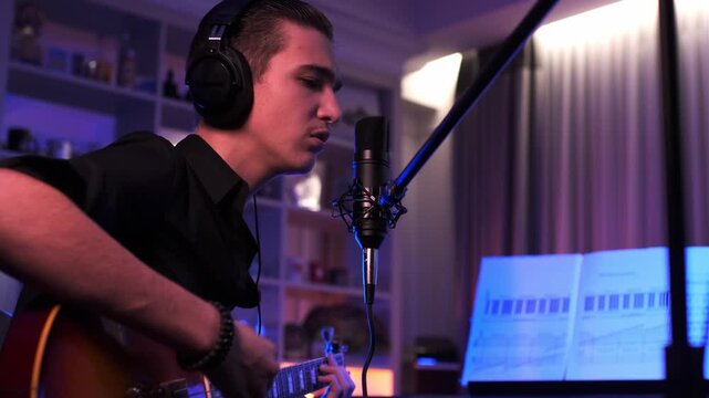 Young Boy sings and plays the electric guitar. Cinematic footage of teenager plays guitar at home. Young man plays a musical instrument. Musician in headset records his composition in a music studio.