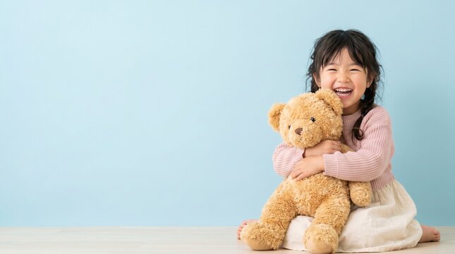 テディベアを抱っこして笑う女の子（コピースペースあり）