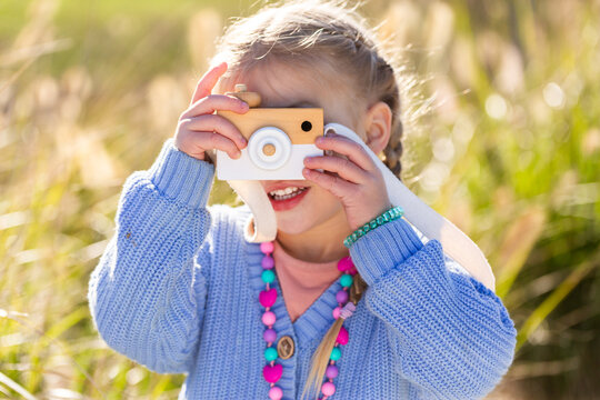 Child playing with toy wooden camera pretending to be a photographer
