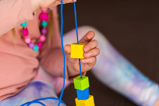preschooler doing beading threading activity with thread and wood bead