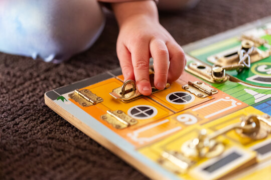 child working on colourful lock puzzle board on floor
