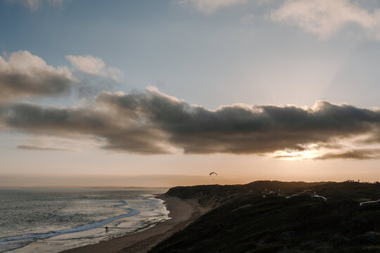 Paraglider soaring gracefully above the ocean at twilight