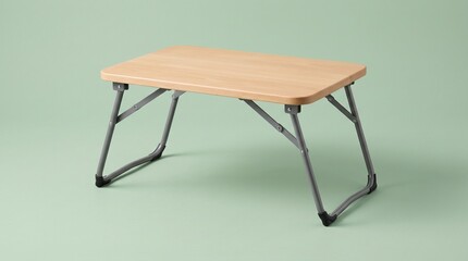 Fototapeta premium A portable folding laptop desk with a light natural wood top and grey metal legs, isolated against a soft sage green background. Ideal for working in bed or on a couch.