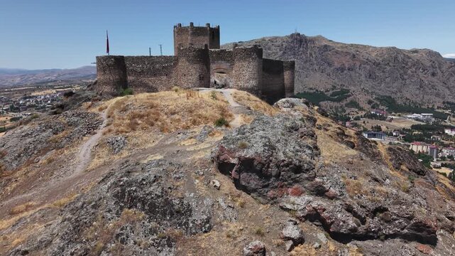 4K cinematic drone slowly pulls back from an ancient fortress, revealing the surrounding cliffs and landscape. Long aerial shot ideal for history, travel, and documentary projects.