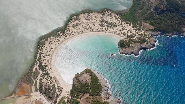 Drone circles around Voidokilia Beach on a sunny day with sunlight reflection in water, Pylos, Messinia, Peloponnese