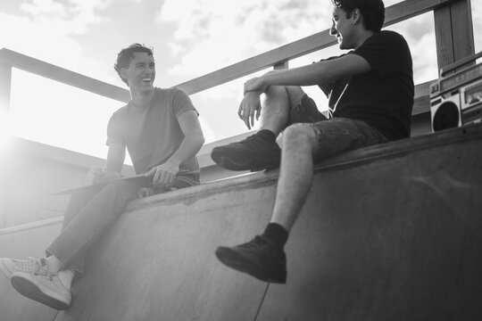 Young friends chatting at skateboard city park during summer time - Gen z lifestyle and extreme sport concept - Main focus on left guy face - Black and white editing - UGC content