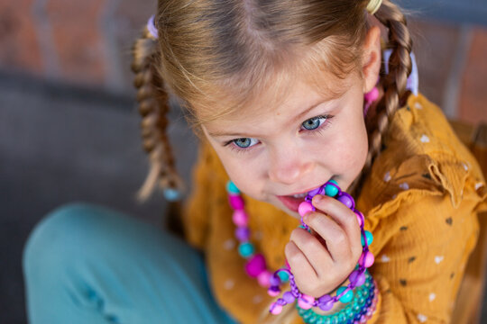 Little girl biting colourful chewelry bracelets for sensory stim