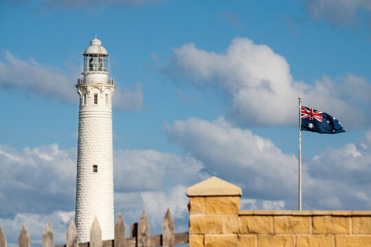 The historic Cape Leeuwin Lighthouse and an Australian flag flying above a brick wall