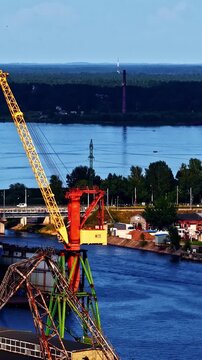 Side-on vertical social ratio aerial video of shipping cranes at the docks in Riga, Latvia. Produced in 1080x1920 and with Rec709 color.