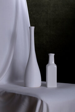 Still life with two white vases on white fabric