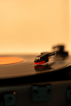 Close-up of a turntable needle playing a vinyl record with warm lighting