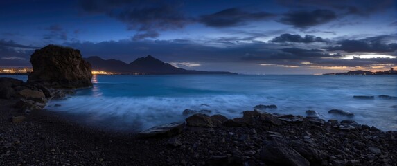 Fototapeta premium Seascape at Dusk with Mountains and Soft Waves on Rocky Shore