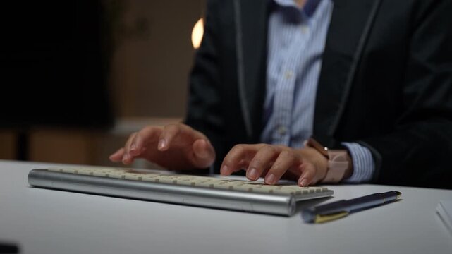 Professional business person typing on a wireless keyboard while working on a computer in a modern office, close up of hands writing an important document or email