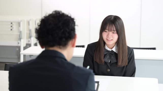 A Japanese high school girl discussing her future with a teacher in a classroom&mdash;a video depicting a cram school or school setting where students talk about their futures with smiles during one-on-one 