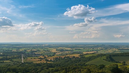 Fototapeta premium Vast Green Countryside Landscape under a Blue Sky with White Clouds