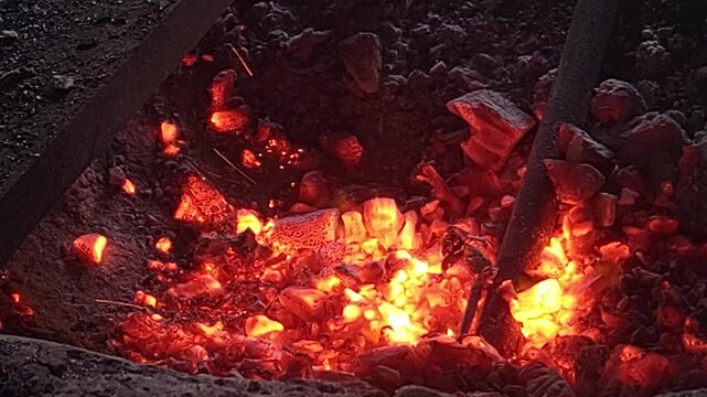 Industrial blacksmith forge blowing wind with intense hot orange sparks flying.