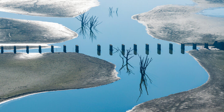Aerial panorama view of a disused railway bridge through muddy banks of a drying reservoir