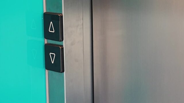 Person pressing elevator call button in modern residential building. Everyday accessibility and vertical transportation improve convenience and mobility