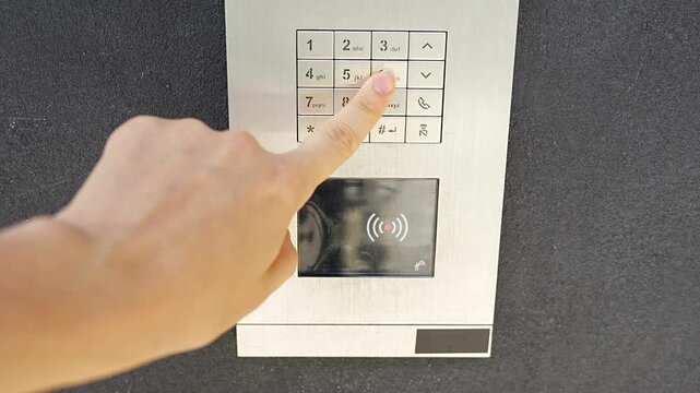 Person entering numbers on residential building intercom keypad. Secure access control enables visitor communication and controlled building entry