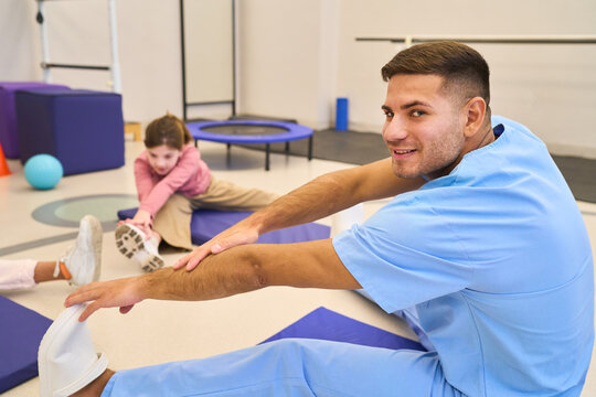 Pediatric physiotherapist assisting children with stretching exercises, rehabilitation session, motor skills training, physical therapy for kids, pediatric rehab center, balance training