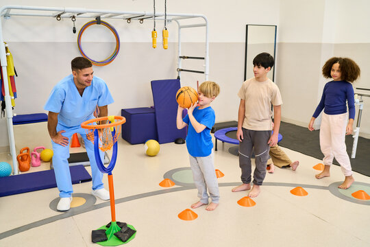 Pediatric Physiotherapy Session with Children, Therapist Assisting with Motor Skills Training, Rehabilitation Exercises in Pediatric Rehab Center, Balance Training
