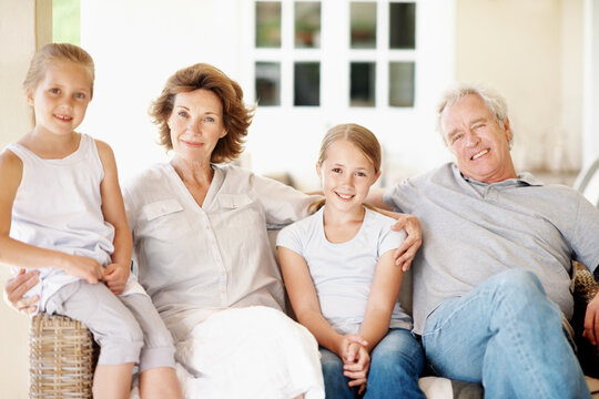 Grandparents, children and happy portrait in home for bonding together, holiday visit and care. Love, senior people or grandkids with hug on sofa for babysitting weekend, family connection or support