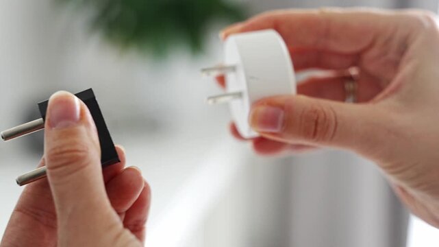 Electrical plug adapters with different socket standards in human hands. International power compatibility concept for travel, electronics and device charging.