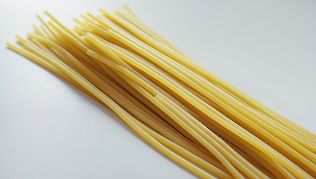 Yellow long spaghetti on White background. Arranged in rows, thin pasta; yellow Italian pasta. Long spaghetti strands. Raw spaghetti wallpaper. Thin spaghetti. Food background theme. Top view.
