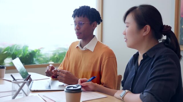 Diverse young colleagues working together on laptop computer in modern office, business collaboration concept